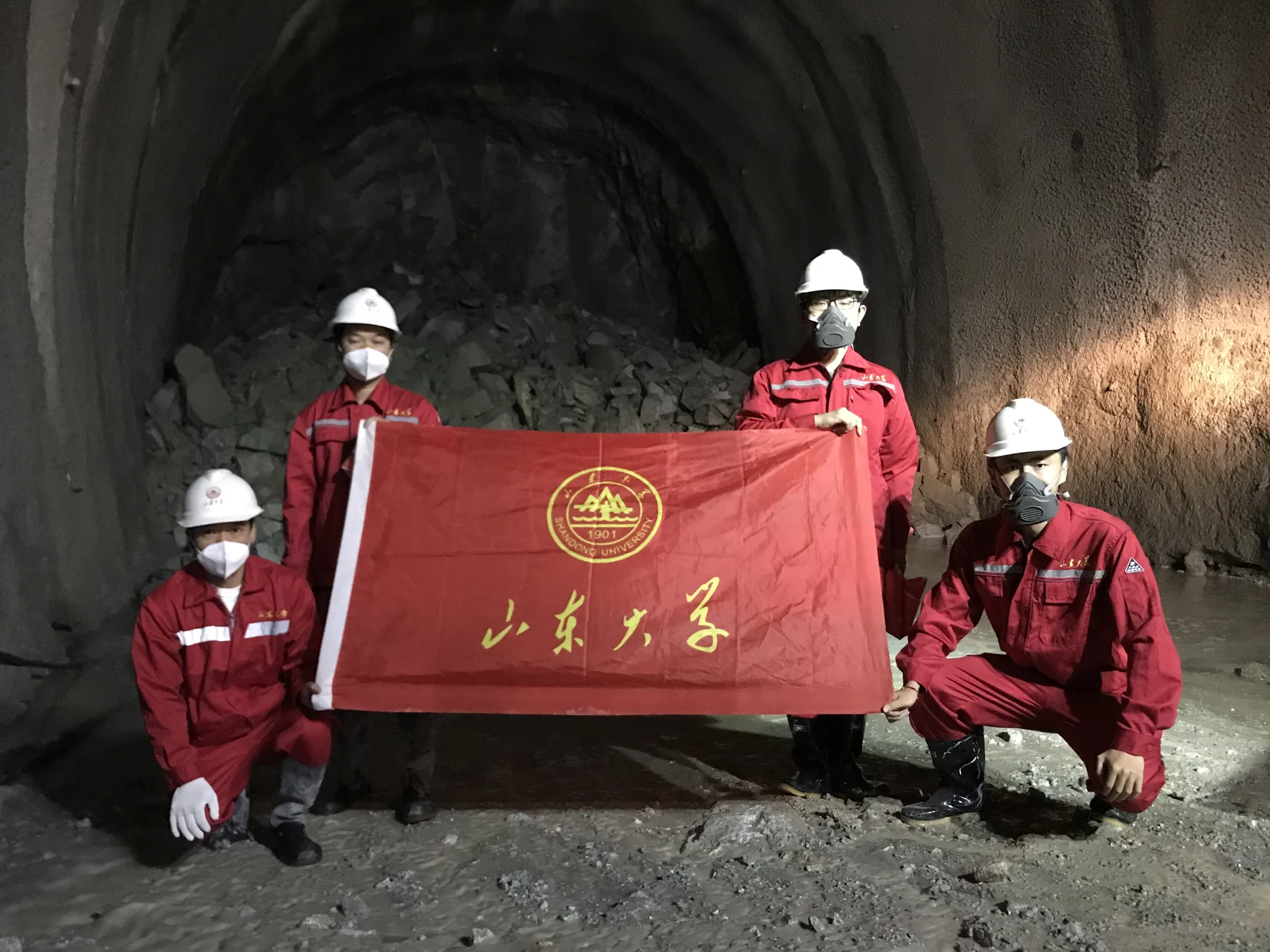 四名工作人员在隧道内手持山东大学旗帜合影